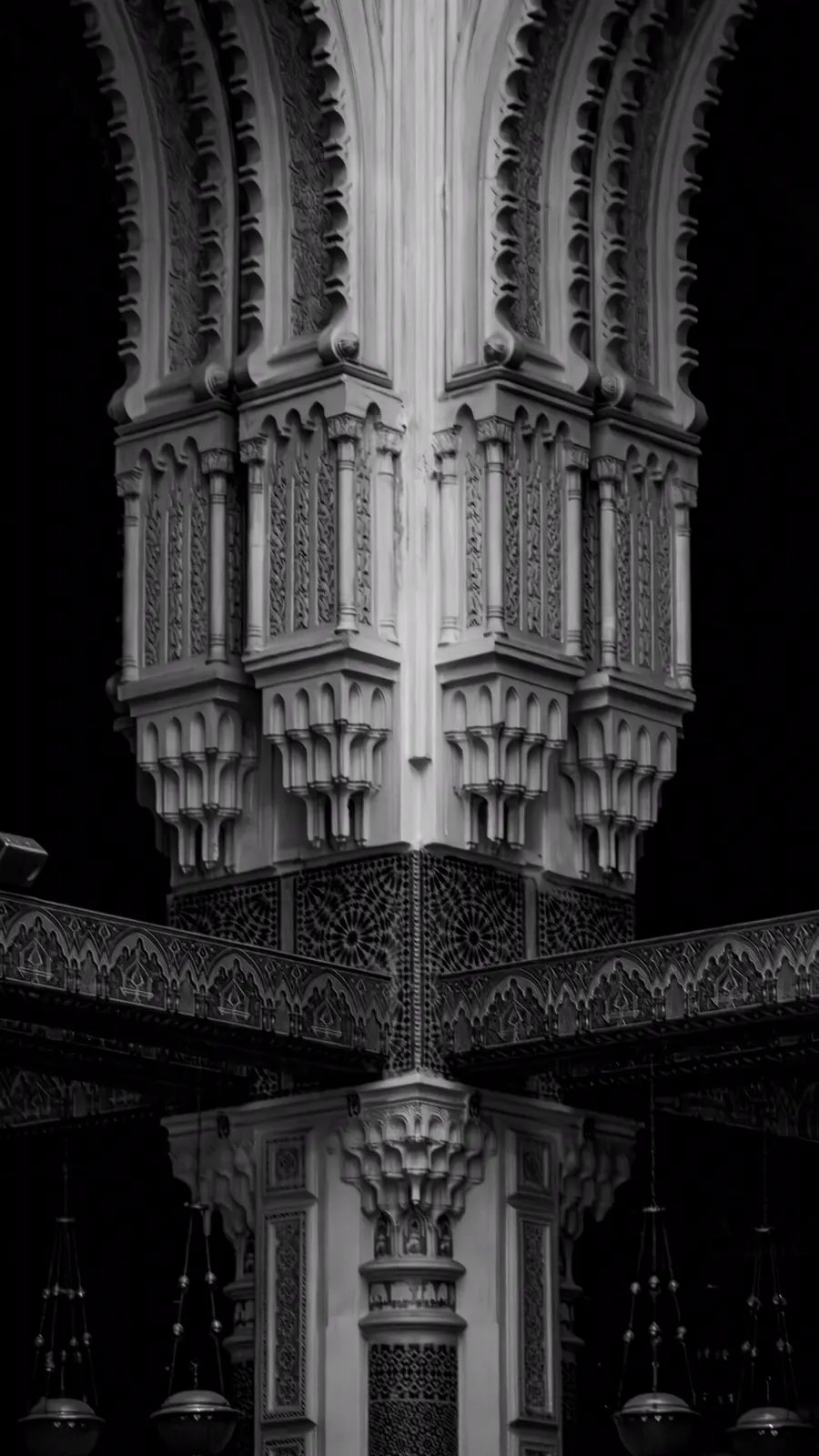 Carved arches and muqarnas of a mosque interior in black and white